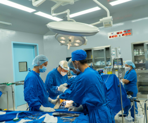A group of surgeons performing surgery Description automatically generated with low confidence